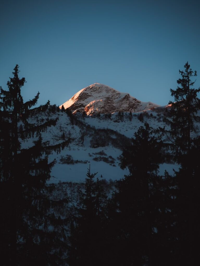 Snowy mountain peak illuminated by sunset light